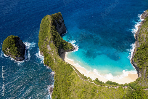 Aerial view of Kelingking Beach, Cap de T-Rex and steep cliffside stairs on sunny day. Nusa Penida Island, Indonesia.