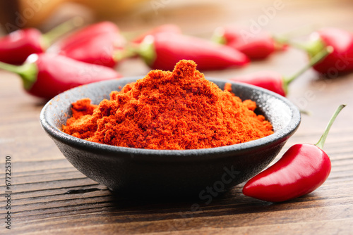 Bowl of red chili pepper ground to powder and whole redred hot pepper pods on background. photo