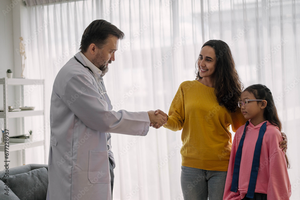 Pediatrician doctor talking to kids with parent in medical clinic. Smiling male doctor to handshake with parent in examination hospital room. Healthcare and medical Kids concept. Pediatrician doctor talking to kids with parent in medical clinic. Smiling male doctor to handshake with parent in examination hospital room. Healthcare and medical Kids concept.