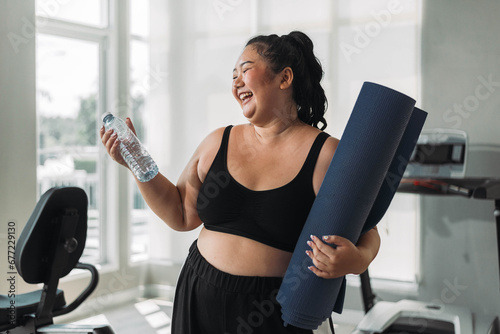 Plus size Asian woman exercises in gym. Beautiful overweight woman in sportswear smiling and happy in fitness. concept of body positive, self-acceptance, weight loss.