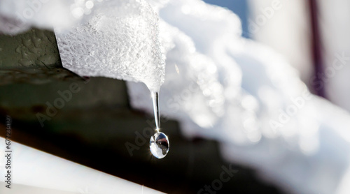 Fotografie a drop of melted snow falls from the roof