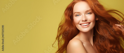 Beautiful elegant european red-haired smiling young woman with perfect skin and long red hair  on a green background  close-up