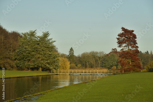 Le canal reliant les pièces d'eau vers la passerelle et l'arbre à feuillage pourpre en fin de journée d'automne au parc de Tervuren à l'est de Bruxelles 