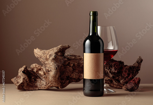 Bottle and glass of red wine with old weathered snag.