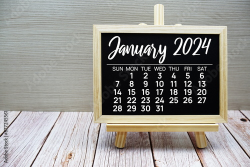 January 2024 monthly calendar on easel stand on wooden background