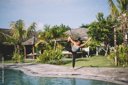 Flexible woman exercising on poolside © BullRun