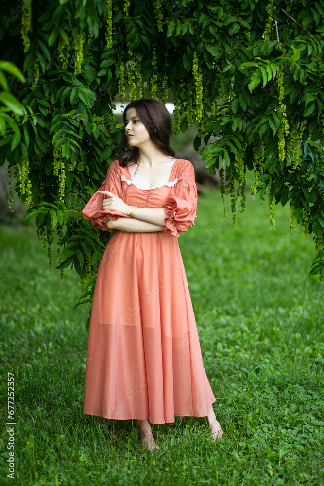 Image of a beautiful brunette female model in dress posing in the park, tree background.
Image of a beautiful brunette female model in dress posing in the park, tree background.