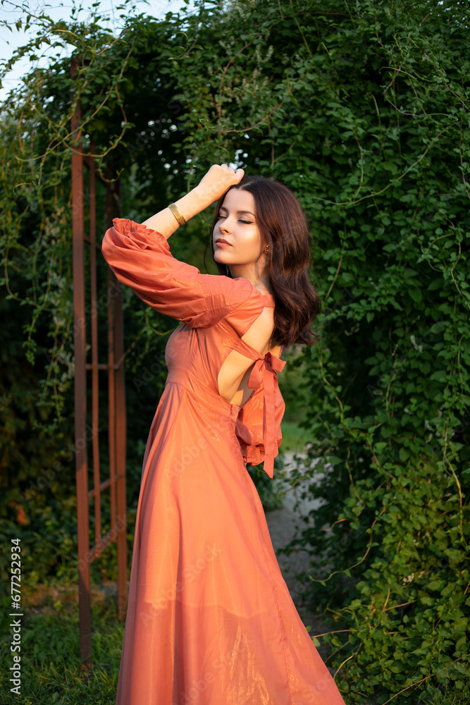 Portrait of a beautiful brunette girl in dress posing in the park, tree background.
Portrait of a beautiful brunette girl in dress posing in the park, tree background.