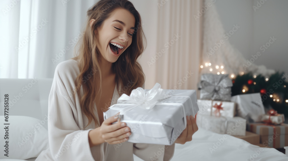 A joyful woman sitting on a bed, laughing with excitement as she holds a Christmas gift with a ribbon A joyful woman sitting on a bed, laughing with excitement as she holds a Christmas gift with a ribbon