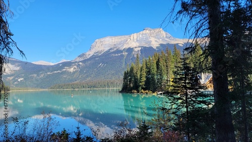 Landscape view of the fir forest trees and mountains reflected i lake against a blue sky