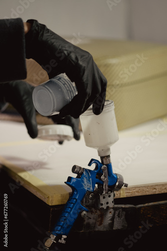 Woman in black protective gloves filling plastic bowl with paint in car workshop. Master adds primer to plastic bowl before before the spraying procedure.
