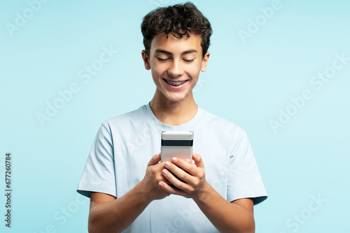 Portrait of happy boy holding mobile phone, text message, chatting, watching video standing