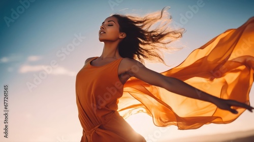 Woman with arms outstretched in dynamic pose wind blown orange dress outdoor wide 