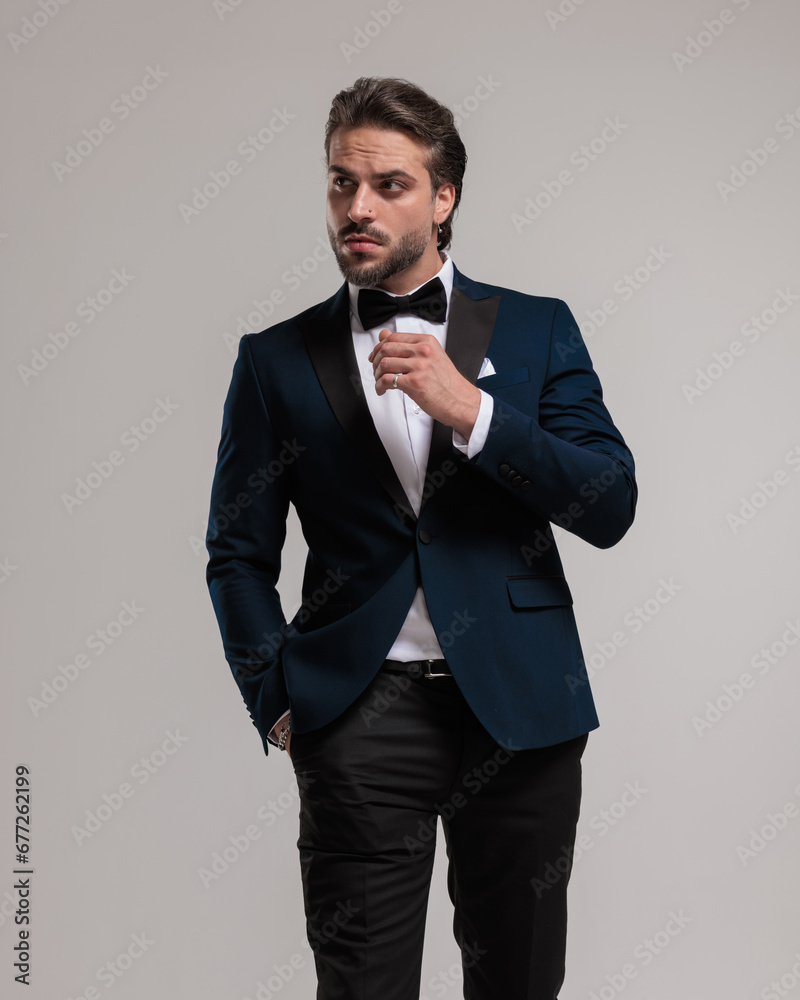 confident elegant businessman in tuxedo looking to side and walking