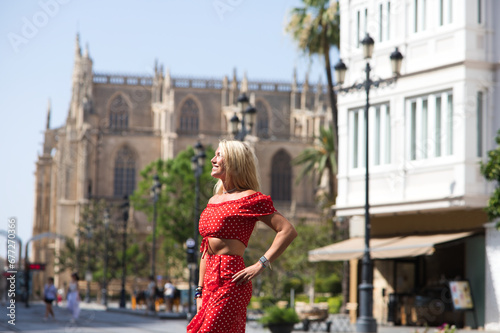 Young and beautiful blonde woman from the United States is on a sightseeing trip to Seville, Spain. The woman is enjoying her holidays in europe. She is between the rails of the urban tram.