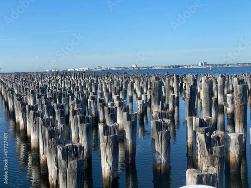 High angle shot of wooden pier poles on blue water © Wirestock
