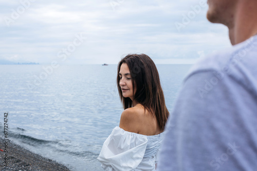 Portrait of a beautiful brunette girl at sea, with a guy in the background