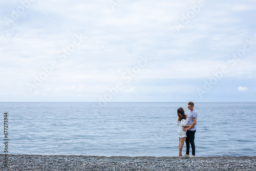 Couple holding hands looking at each other on the beach against the background of the sea