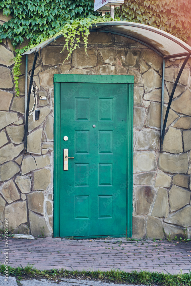 An old wooden door on the stone wall of a village house. Green closed door with copy space. High quality photo