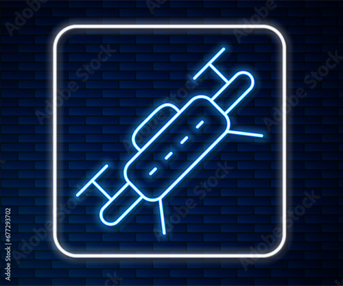 Glowing neon line Drone flying icon isolated on brick wall background. Quadrocopter with video and photo camera symbol. Vector