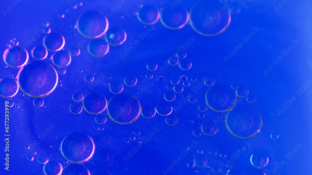 Abstract background. Bubbles liquid. Oily surface. Fat drop circles moving spreading in neon blue shimmering glitter water in creative captivating art.