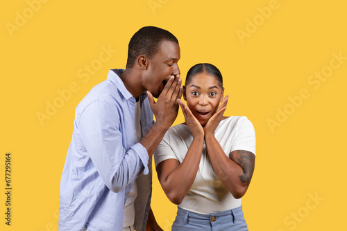 Black man whispers to surprised woman photo