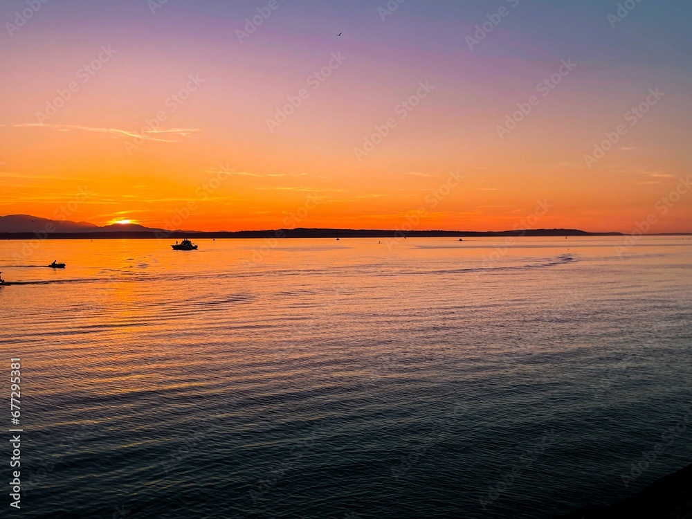 a sunrise with small boats in the water and a large island