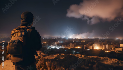 A man with a backpack stands on the edge of a cliff and looks at the night city.