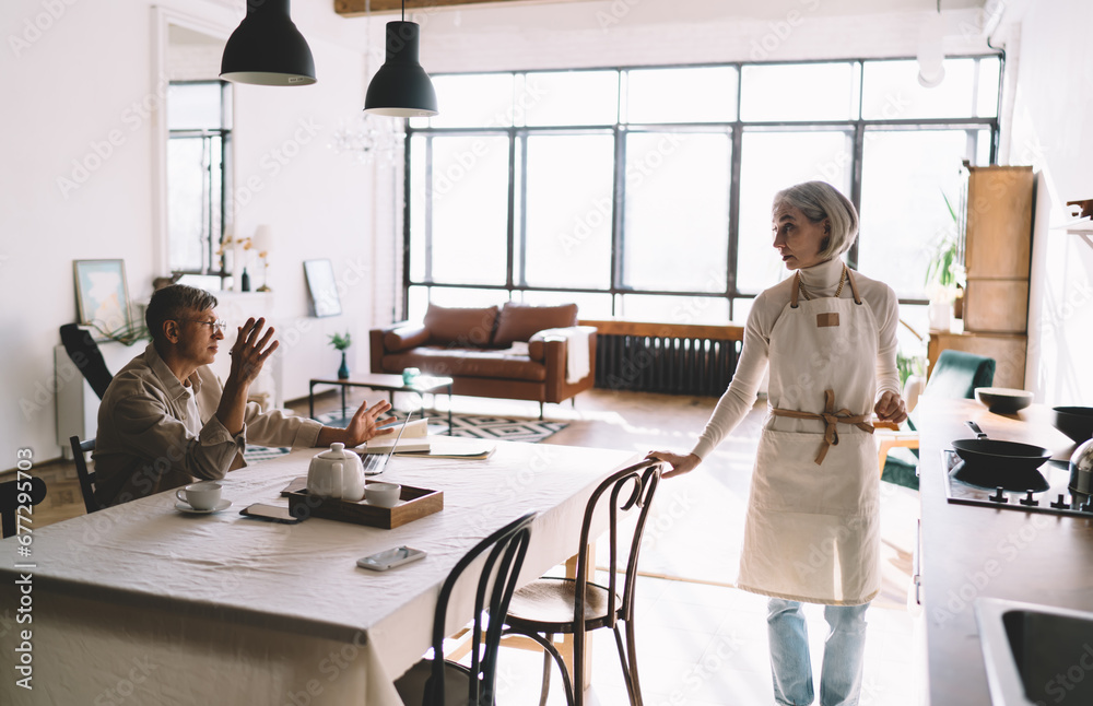 Senior couple speaking and spending time together in kitchen