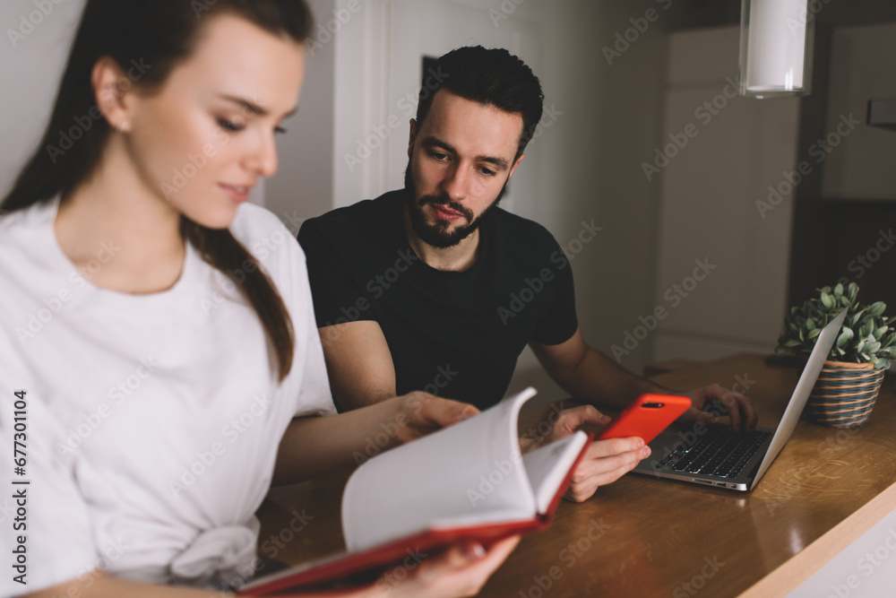 Concentrated young couple searching phone number in notepad Concentrated young couple searching phone number in notepad