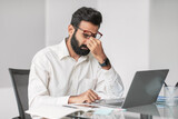Stressed indian businessman at desk with laptop