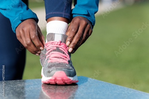 Close-up of unrecognizable black woman tying trainer shoelaces.