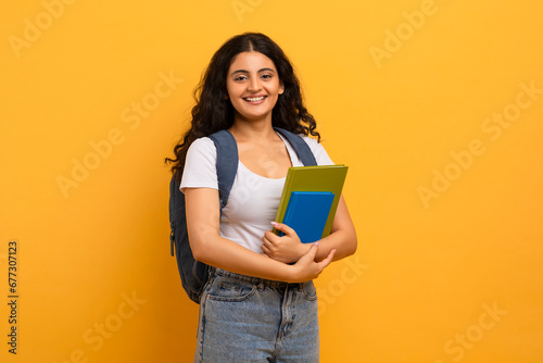 Fotografia Positive indian woman student holding notebooks looking at copy space