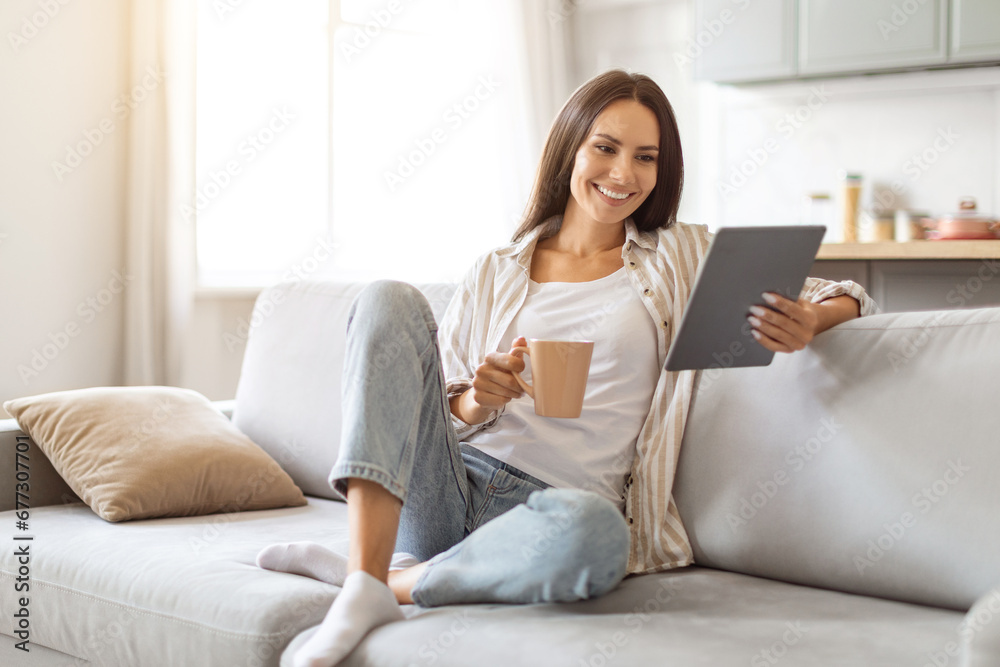 Smiling Young Woman Using Digital Tablet And Drinking Coffee At Home Smiling Young Woman Using Digital Tablet And Drinking Coffee At Home