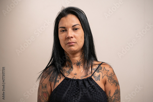 Fotografija Young tattooed woman looking seriously at the camera on a pastel background
