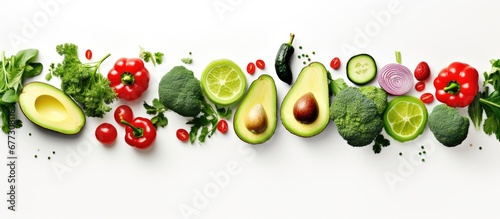 Fototapeta Avocado lime broccoli green pepper cucumber chilli pepper and zucchini arranged creatively in a flat lay depicting a food concept Green vegetables depicted on a white background Copy space imag