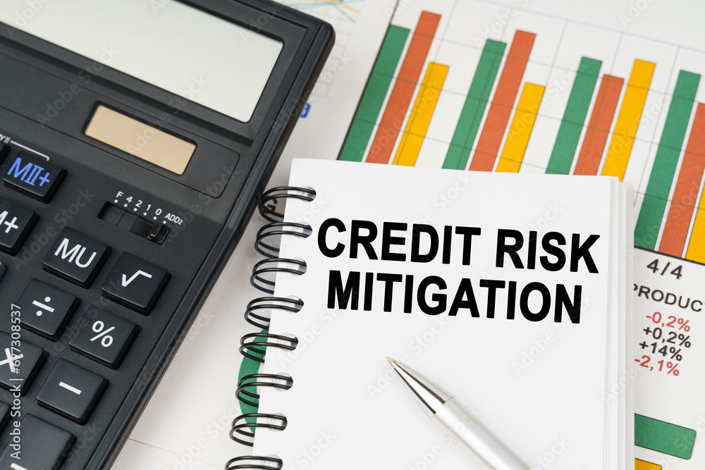 On business charts there is a calculator, a pen and a notepad with the inscription - CREDIT RISK MITIGATION On business charts there is a calculator, a pen and a notepad with the inscription - CREDIT RISK MITIGATION
