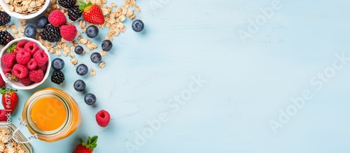 Assorted healthy breakfast ingredients in open jar granola yogurt fruit honey mint on blue background with white board Copy space image Place for adding text or design