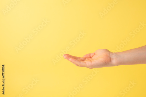 Open hand as if taking some object on yellow background. Copy space