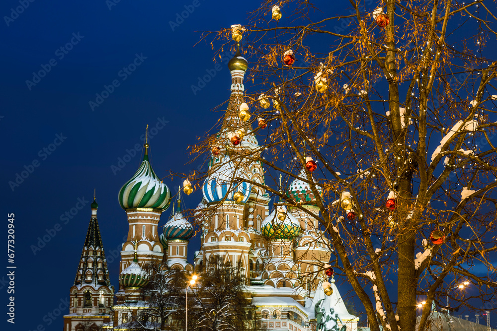 Colorful christmas balls on trees against the background of St. Basil's Cathedral in the evening illumination. Moscow, Russia