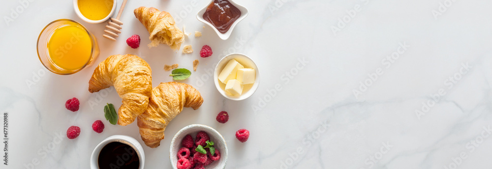 Continental breakfast with croissants, orange juice and cup of coffee on white marble background with copy space top view