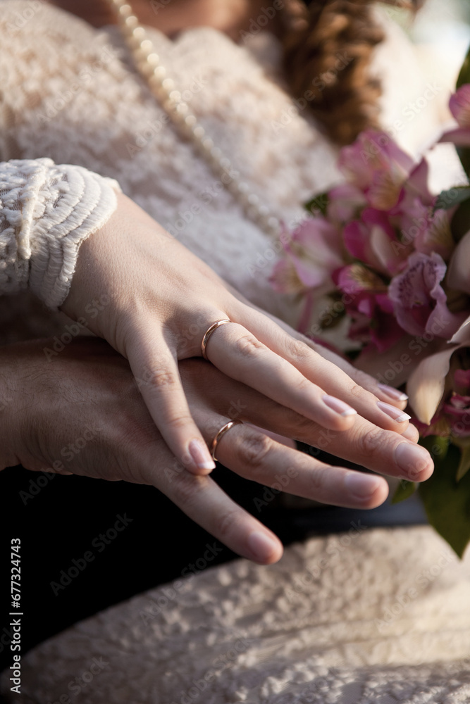 Wedding rings on fingers. Newlyweds with a bouquet of flowers