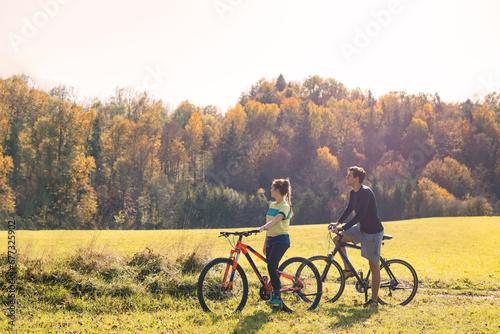 Young smiling, relaxed couple enjoying a bike ride in a beautiful countryside. Active autumn vacation concept.