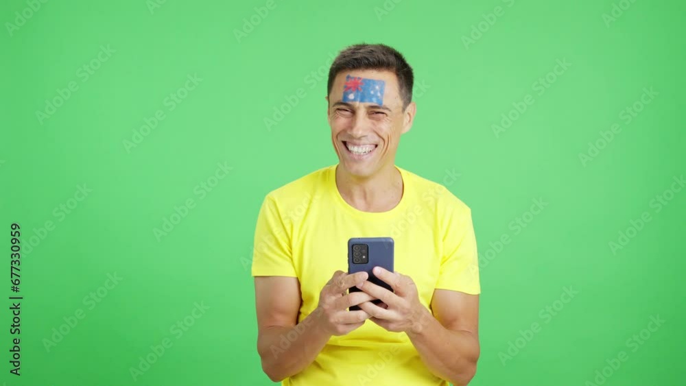 Australian supporter looking at his mobile smiling and showing it. Australian supporter looking at his mobile smiling and showing it.