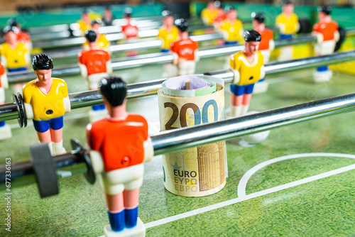 Table football game with a roll of euro bills in front of a red player, concept of betting and victory, sports money