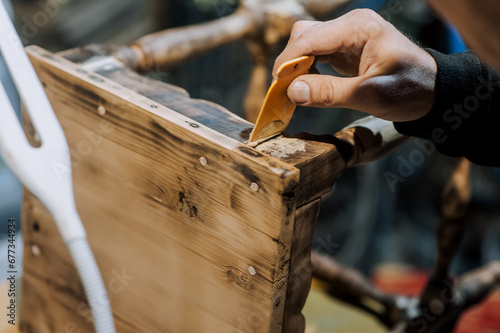 A man is a professional carpenter, a woodworker, applying putty and cement to a wooden chair in the workshop. Photography, handmade concept.
