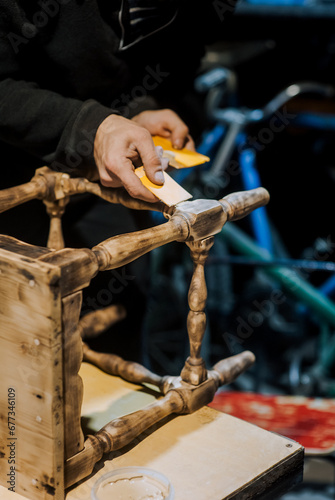 A man is a professional carpenter, a woodworker, applying putty and cement to a wooden chair in the workshop. Photography, handmade concept.