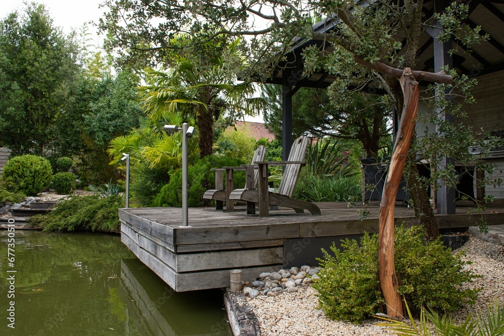 Japanese-style landscape with wooden chairs and bord near a pond Japanese-style landscape with wooden chairs and bord near a pond