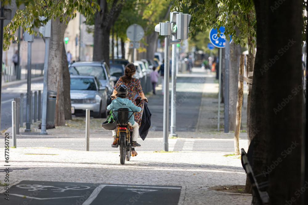 Obraz premium A woman with child riding a bike down a street