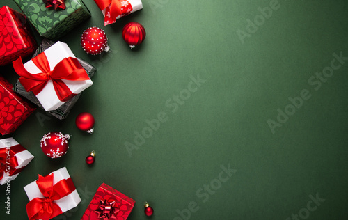 Merry Christmas and Happy Holidays greeting card, frame, banner. New Year. Noel. Red Christmas ornaments and gift on green background top view. Winter xmas holiday theme. Flat lay